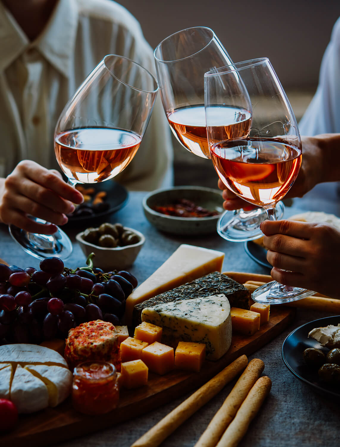 Personer skåler med vin over et bord med snacks