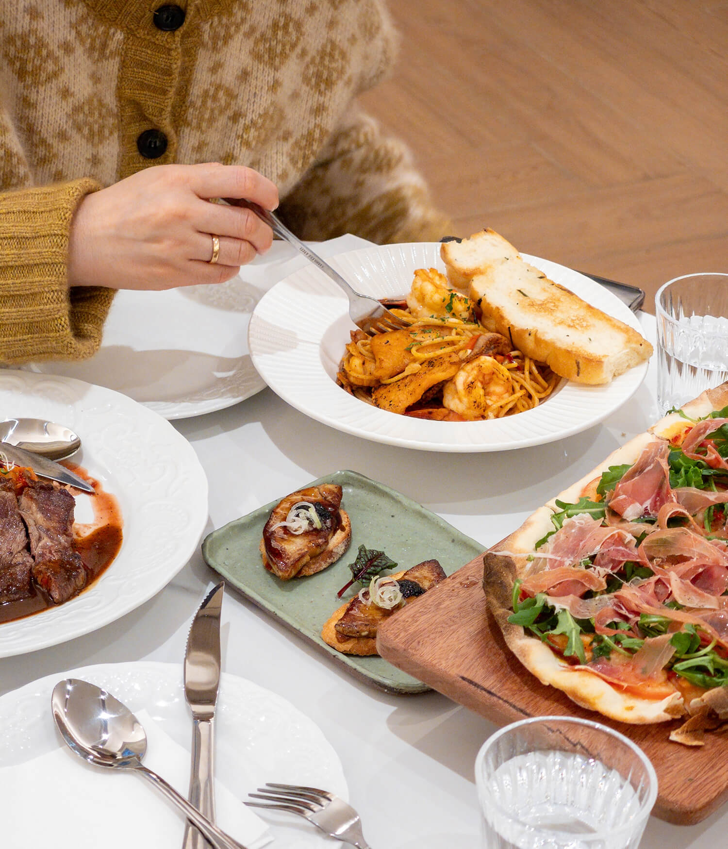 Person spiser en pastaret ved et bord med flere serveringer